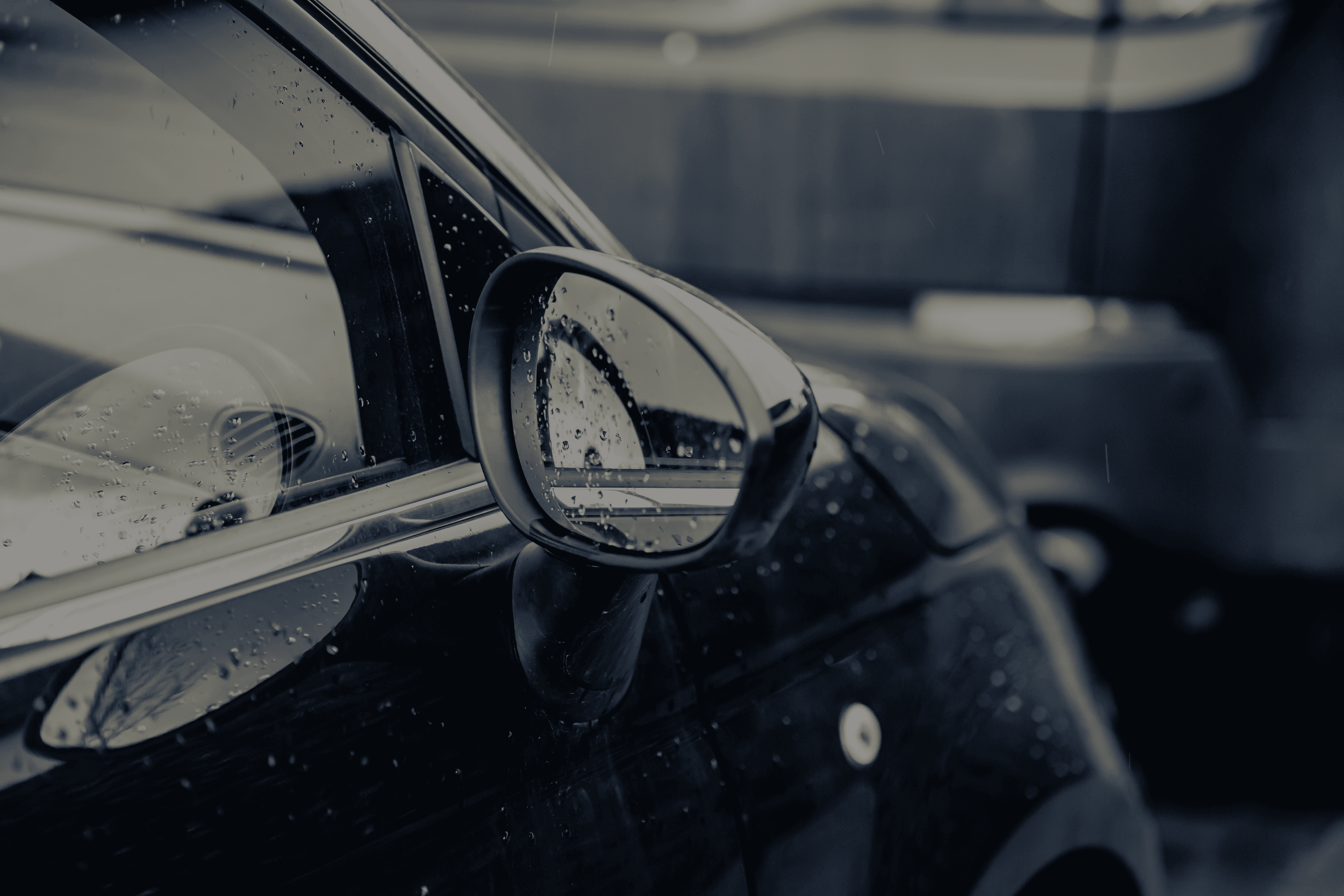 closeup-rearview-mirror-black-car-covered-raindrops_darker.png